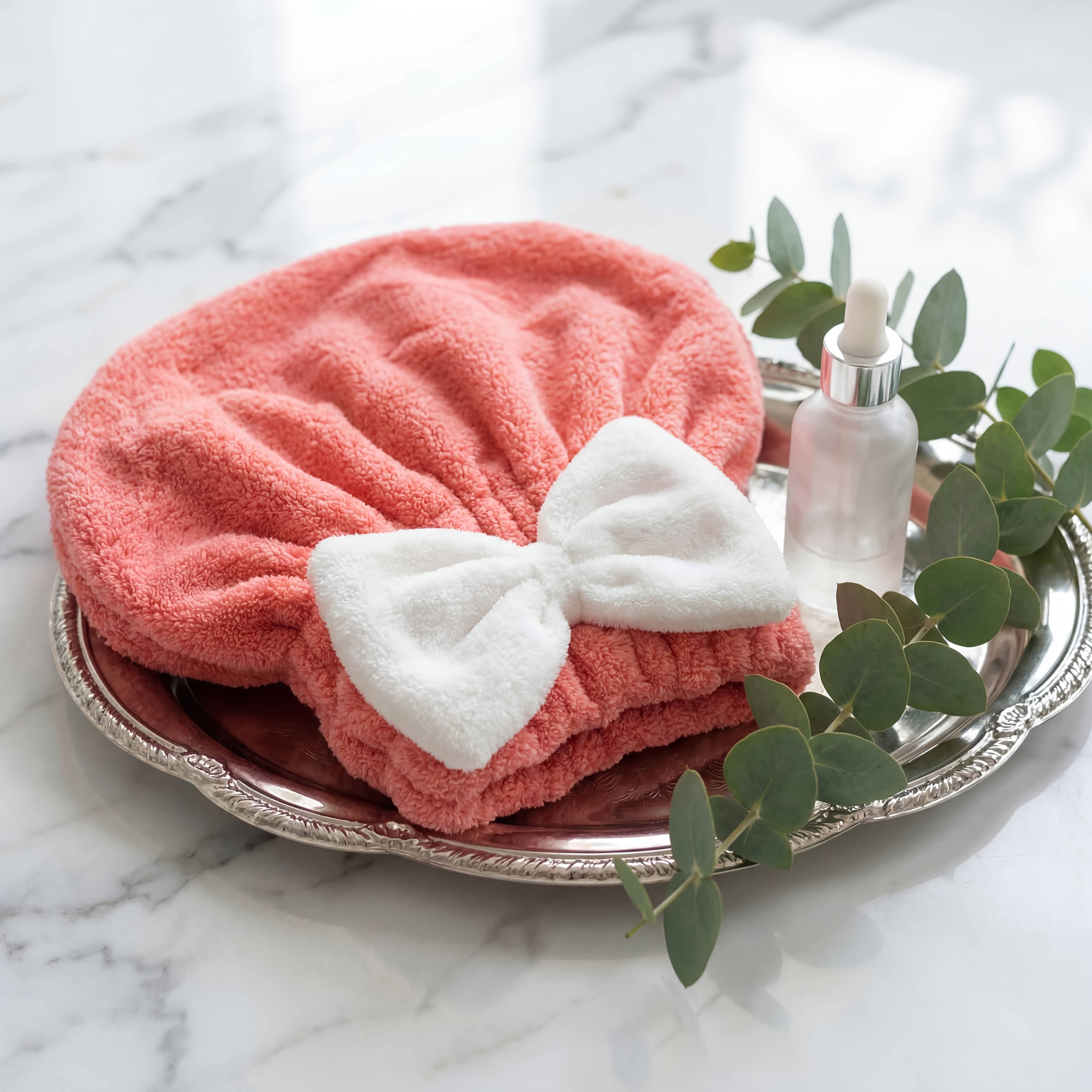 product-fancy-6304f17c-4752-46e7-8853-3ba8109addea - Boubouonaturel – Vêtements, accessoires et produits naturels Pink fluffy towel folded on a silver tray with eucalyptus sprigs on a marble surface, suggesting a spa setup.